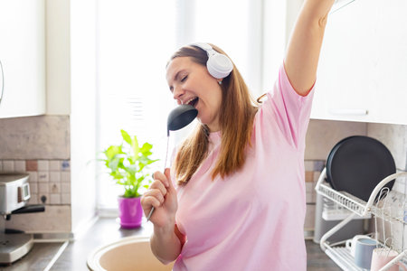 Woman in earphones listening to music while cooking in the kitchenの写真素材