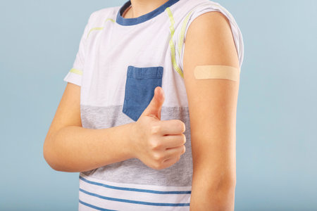 Vaccinated boy gesturing with thumbs up, showing hand with plaster castの写真素材