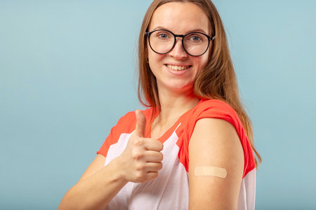 Vaccinated woman in glasses is gesturing with thumbs upの写真素材