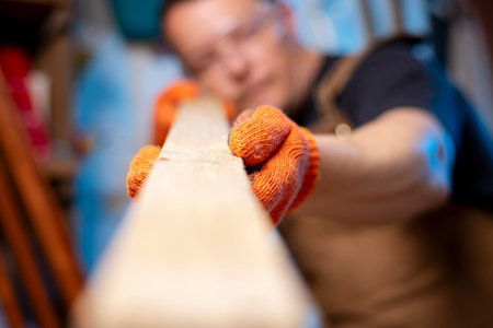 A carpenter checking smoothness of wood material. Woodworker preparing planksの写真素材