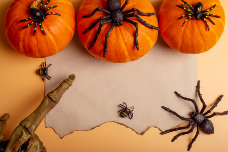 Sheet of paper with spiders, bats, pumpkin and monster hand on orange backgroundの写真素材