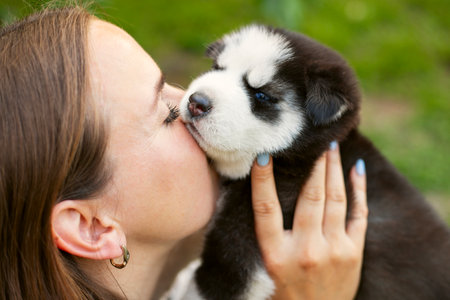 Beautiful young caucasian woman is playing with her puppy dog outdoorの写真素材