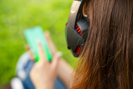 A woman is holding a smartphone and listening to music on headphonesの写真素材