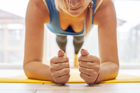 Young sports woman on a yoga mat doing the plank pose.
