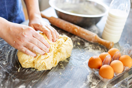 Female hands making dough for baking on wooden table