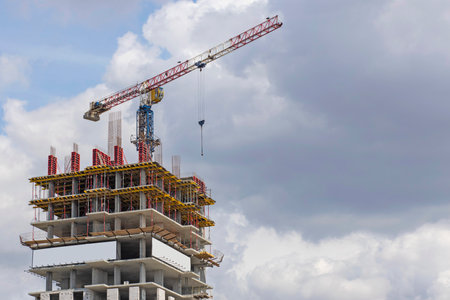 Construction site. A large construction crane against a blue sky builds a houseの写真素材