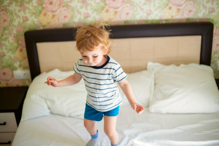 Just a woken up little child jumping on the bed.の写真素材