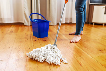 Young woman in protective gloves washing a wooden floor with a mopの写真素材