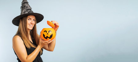 Happy young woman in halloween witch costume with pumpkin basket jack-o-lanternの写真素材