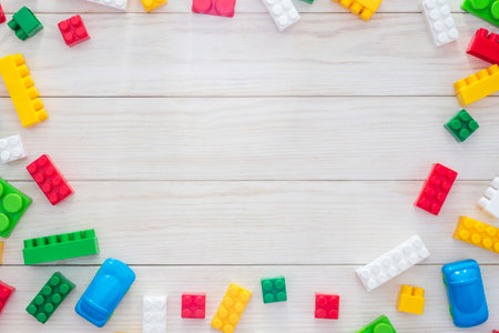 Colorful plastic construction blocks on white wooden background
