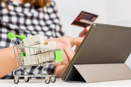 Paper boxes in trolley woman holding credit card and using tablet to shop onlineの写真素材