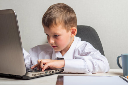 A kid businessman with glasses with laptop working in office