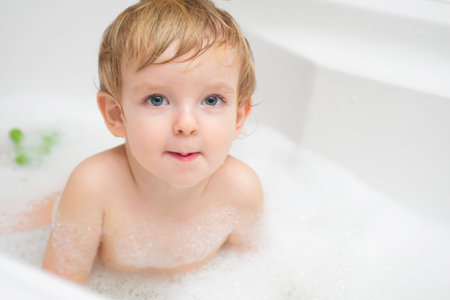 Funny little boy getting a bath in the bathroom.