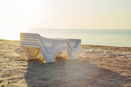 Folded plastic deck chairs on a deserted beach by the sea.
