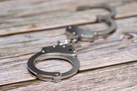 The metal handcuffs on wooden background. Handcuff or shackle. Police handcuffs