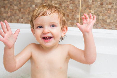 Funny little boy getting a bath in the bathroom.