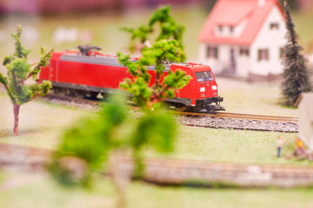 Set of red electric train model and layout with whole scene with trees and houseの写真素材