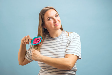 Beautiful brown-haired woman brushing her beautiful shiny hair with hairbrush