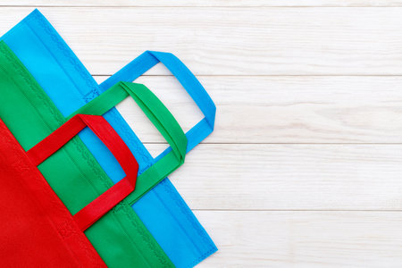 Colorful shopping bags on white wooden background. Mockup for design. Shopping and sale conceptの写真素材