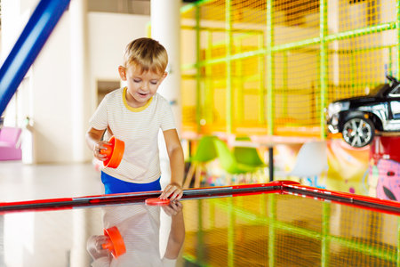 A cute kids playing with a puck in an air hockey in an amusement parkの写真素材