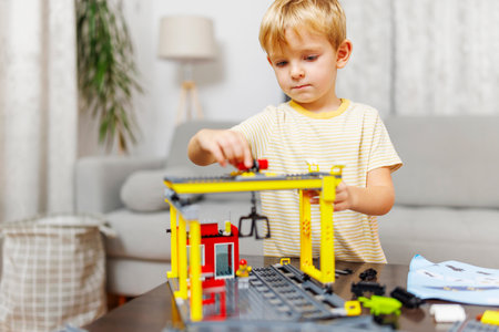 Child boy playing and building with colorful plastic bricks at the table