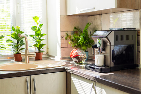 Modern electric coffee machine with cup on countertop in kitchenの写真素材