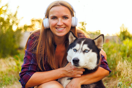 Smiling Woman Hugging Her Husky Dog Outdoorsの写真素材