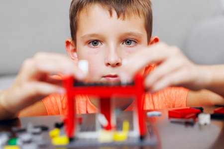 Boy Intently Assembling a Red Toy Building Set