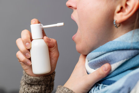 Person Using Throat Spray for Sore Throat Reliefの写真素材
