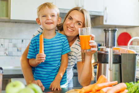 Joyful Mother and Son Enjoying Fresh Carrot Juice at Homeの写真素材