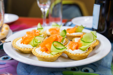 Tartlets with cream cheese, smoked salmon, and cucumber on a festive plateの写真素材