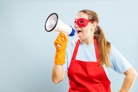 Woman with Megaphone Wearing Red Apron and Superhero Eye Maskの写真素材