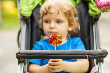 Toddler Holding Lollipop in Stroller