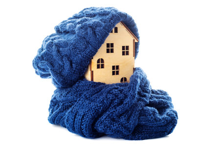 Wooden toy house with warm hat and scarf isolated on white backgroundの写真素材