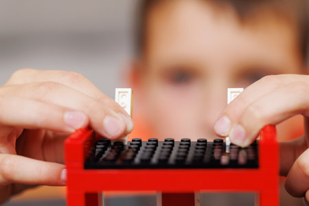 Child building a red toy structure with blocks on a tableの写真素材