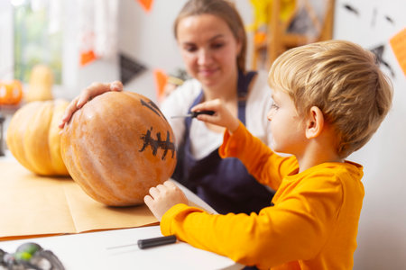 Child painting face on pumpkin for Halloweenの写真素材