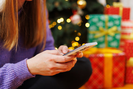 Woman texting on smartphone with Christmas giftsの写真素材