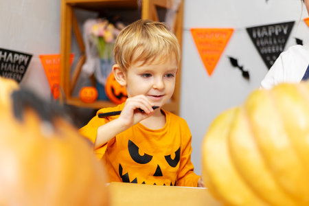 Young boy carving pumpkin at Halloween tableの写真素材