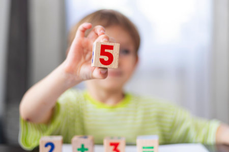 Child holding wooden number block in classroomの写真素材