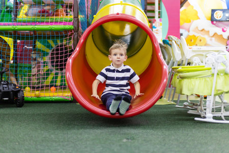 Boy sliding down colorful indoor tube slideの写真素材