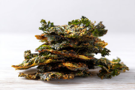 Stack of Crispy Baked Kale Chips with Seasoning on White Surfaceの素材
