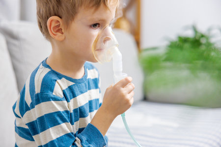 Child Using Nebulizer for Breathing Treatment at Homeの写真素材