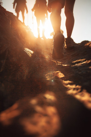 Close-up silhouette of hikers' legs on a rocky ridge, captured in cinematic motion. Sunlight streams behind, creating a dynamic and minimalist tone, emphasizing realism and adventure.の素材