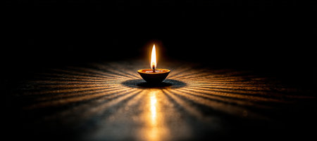 A single diya flame casts a warm glow in a dark room, creating deep shadows and a spiritual ambiance. This minimalistic composition symbolizes light and tranquility.の素材