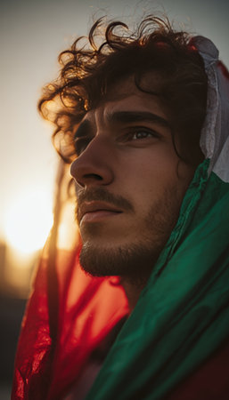 An Italian football supporter is wrapped in the tricolor flag, displaying a look of determination. The scene is set against a cinematic sunset glow with a shallow focus.の素材