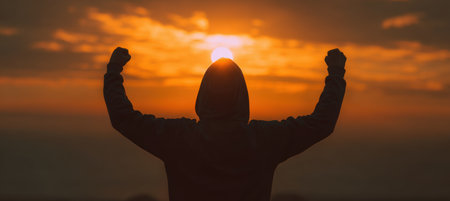A person in a hoodie stands triumphantly under a glowing sunrise sky, embodying a motivational sports aesthetic. The scene captures a sense of achievement and inspiration.の素材