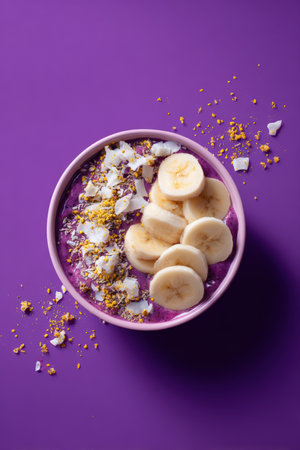 A visually striking acai smoothie bowl topped with sliced banana, coconut, and bee pollen, set against a vibrant purple background. Perfect for digital advertising and healthy food promotions.の素材