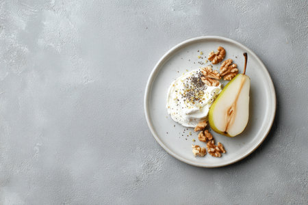 A clean white plate with cottage cheese, sliced pear, chia seeds, and walnuts on a textured grey background. Ideal for food blogs or product photography with a minimalist style.の素材