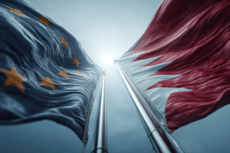 European Union and Bahrain flags gracefully wave on steel poles under bright light. The wide-angle view captures the airy mood and realism of the scene.の素材