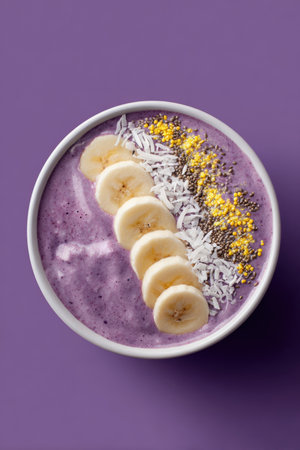 A visually appealing acai smoothie bowl topped with sliced banana, coconut, and bee pollen on a vibrant purple background. Perfect for digital ads and healthy lifestyle promotions.の素材